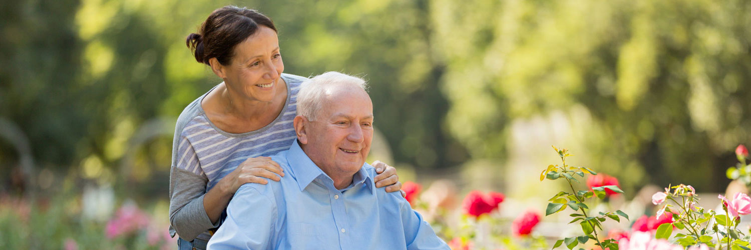 Caregiver and elderly man looking at flowers